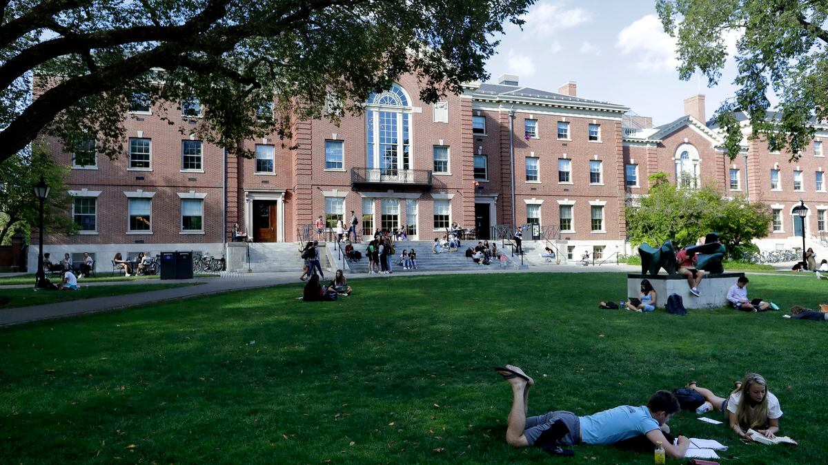 In this Wednesday, Sept. 25, 2019 photo, people rest on grass while reading at Brown University, in Providence, R.I.