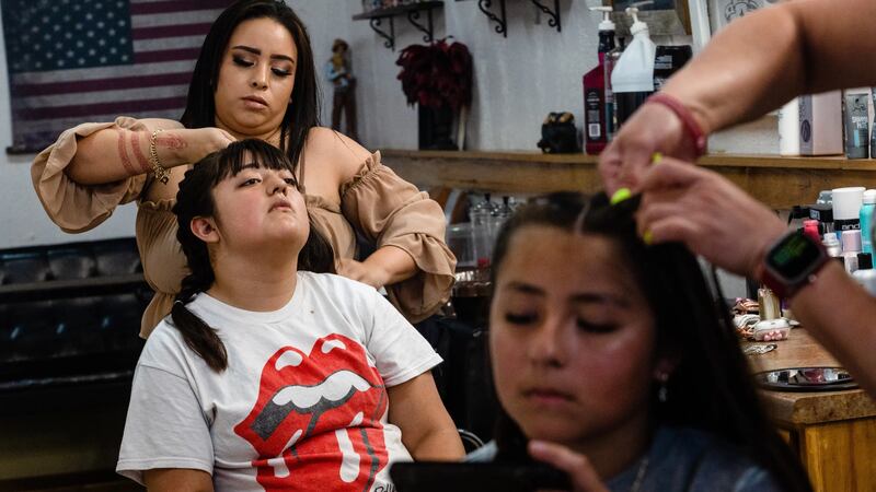 Illiaña Treviño and her sister Ameliaña have their hair braided at the Plaza Barber Shop